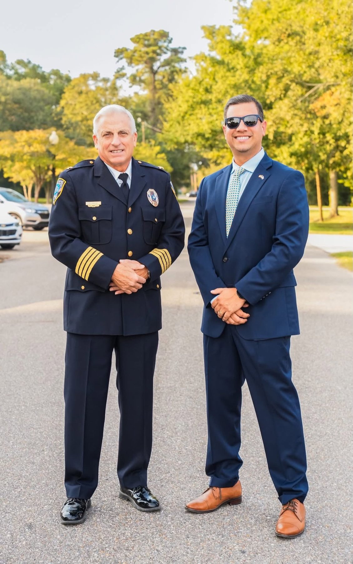 Daniel Seuzeneau in a navy suit standing with Slidell's police chief in dress uniform
