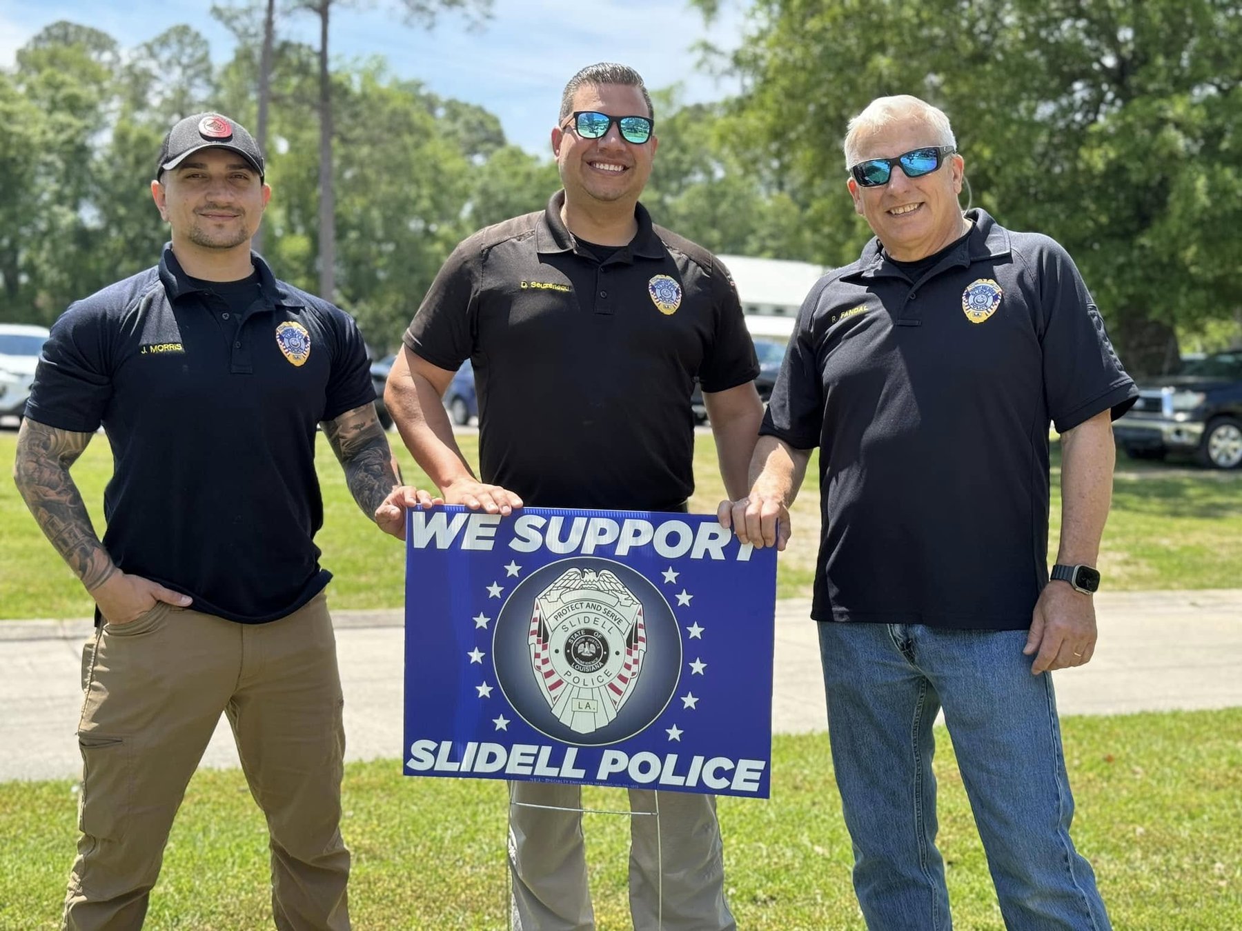 Daniel Seuzeneau and two fellow officers holding a We Support Slidell Police yard sign